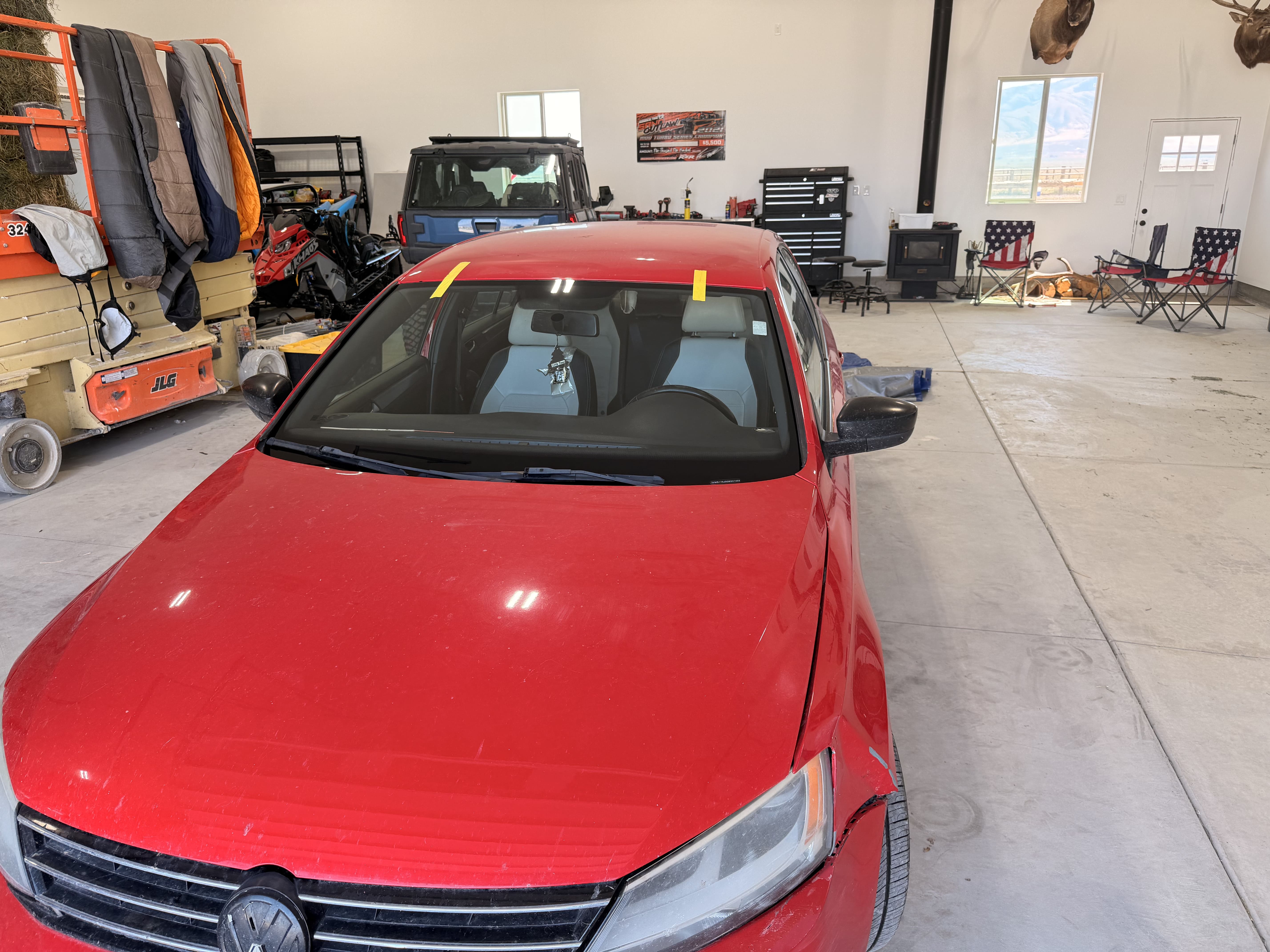 Red sedan with new windshield taped in place